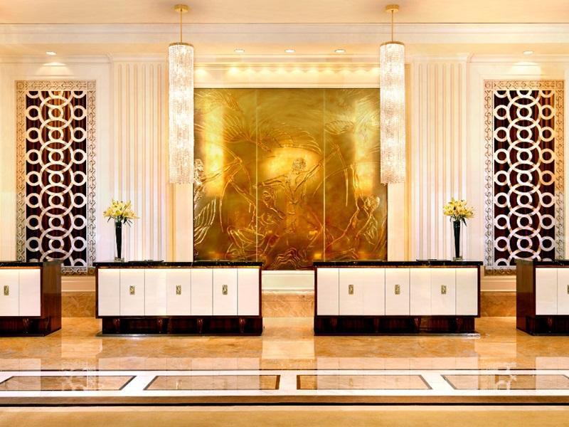 Trump International Hotel Лас Вегас Екстериор снимка The photo depicts a luxurious reception area or lobby of a hotel. It features multiple elegant reception desks with a combination of dark wood and white cabinetry. Behind the desks, there is a large, striking golden artwork that adds an opulent touch