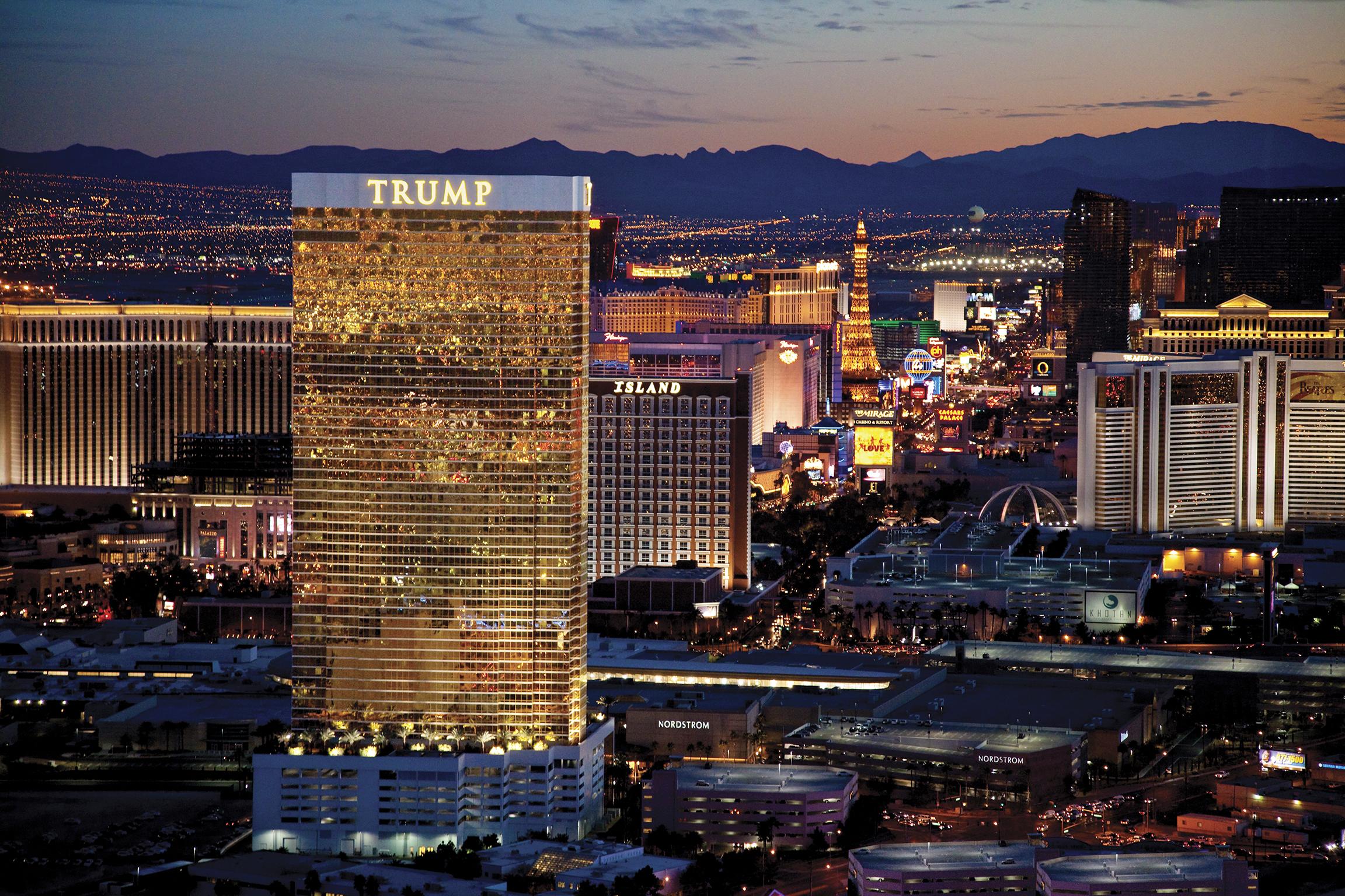 Trump International Hotel Лас Вегас Екстериор снимка The image features a nighttime view of the Las Vegas Strip. Prominently displayed is a tall hotel building, which is illuminated and features the name "TRUMP" at the top. Surrounding it are various other buildings and attractions typical of the vibra