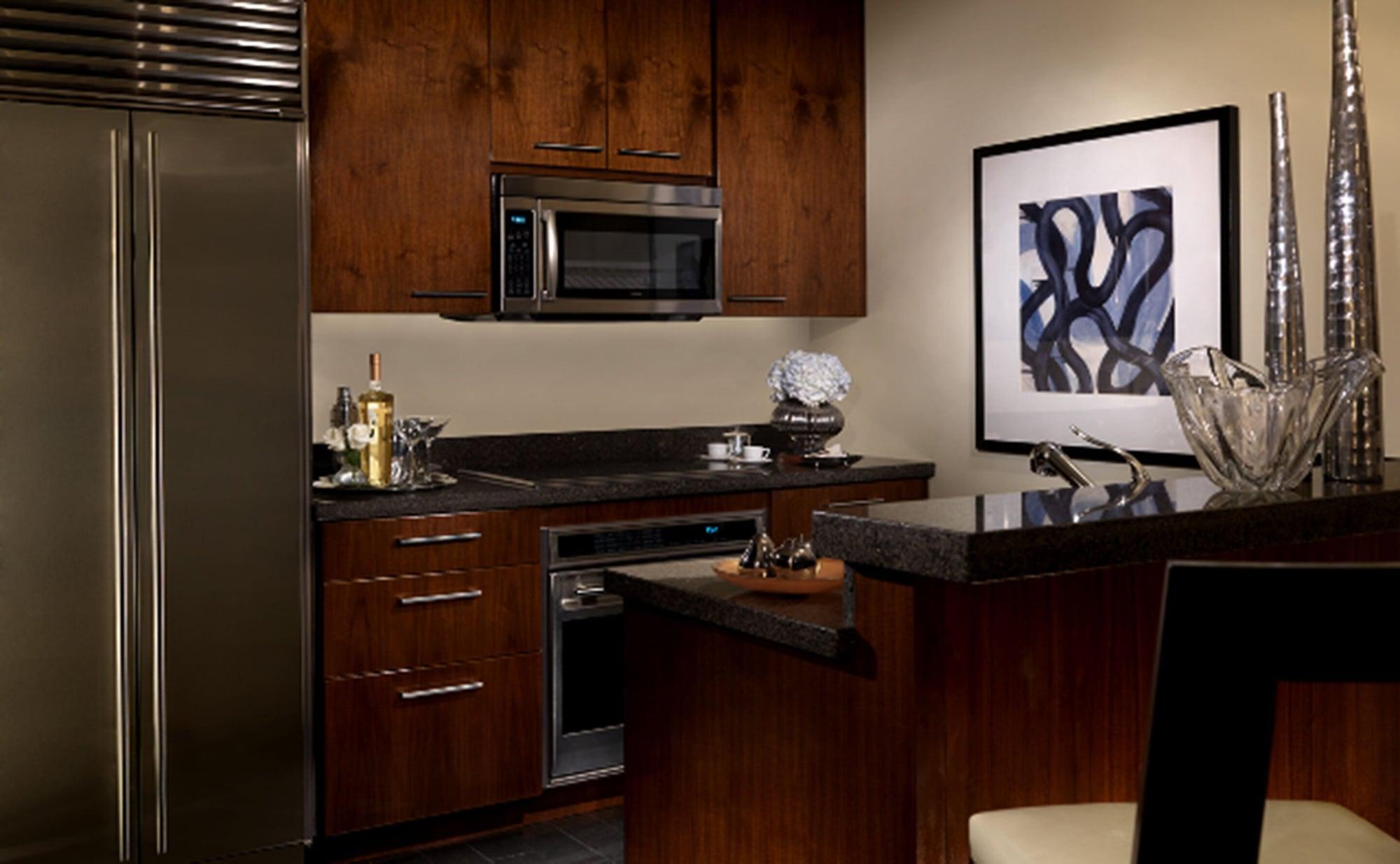 Trump International Hotel Лас Вегас Екстериор снимка The photo features a modern kitchen with elegant design elements. The cabinetry is a rich, dark wood, which provides a warm and sophisticated aesthetic. 

There is a stainless steel refrigerator on the left side and built-in appliances, including a m