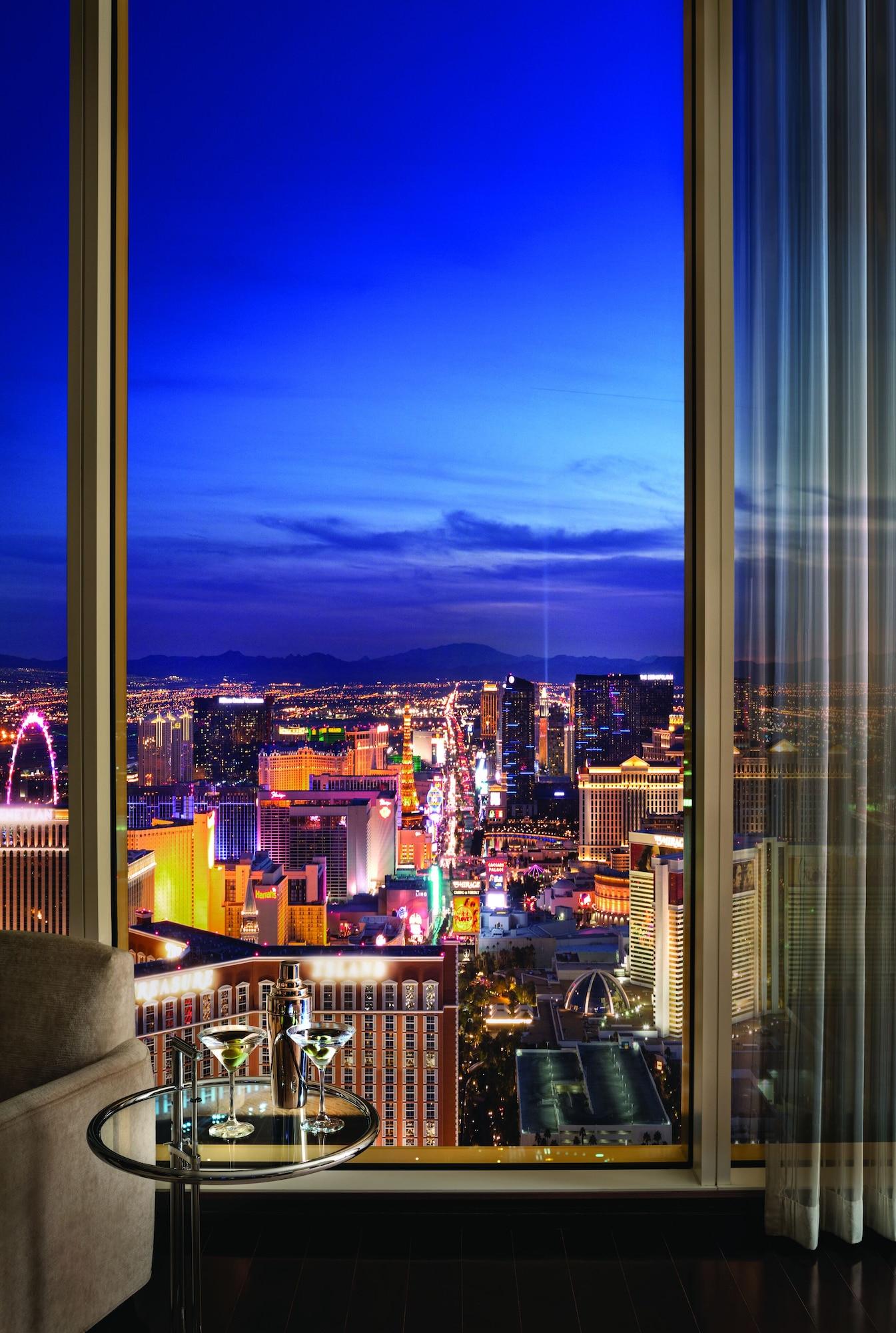 Trump International Hotel Лас Вегас Екстериор снимка The photo showcases a stunning night view of a vibrant city, likely Las Vegas. Through a large window, you can see the city skyline illuminated by numerous bright lights from various buildings and attractions. The skyline is lively, with iconic struc