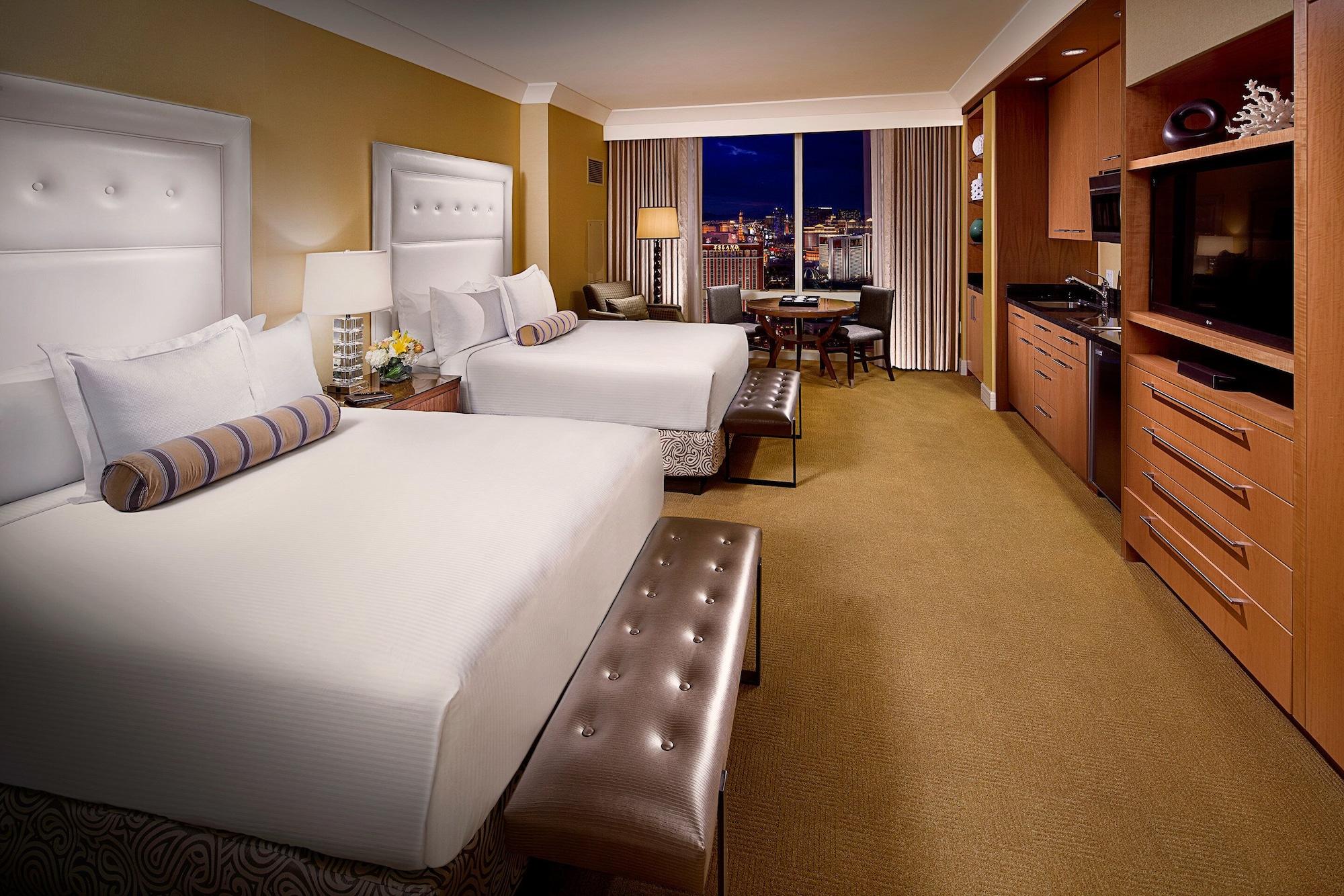 Trump International Hotel Лас Вегас Екстериор снимка The photo shows an elegantly designed hotel room featuring two queen-sized beds with stylish white headboards. There is a bench at the foot of the beds with a tufted design. The room has warm, neutral tones, with light coming in from a large window t