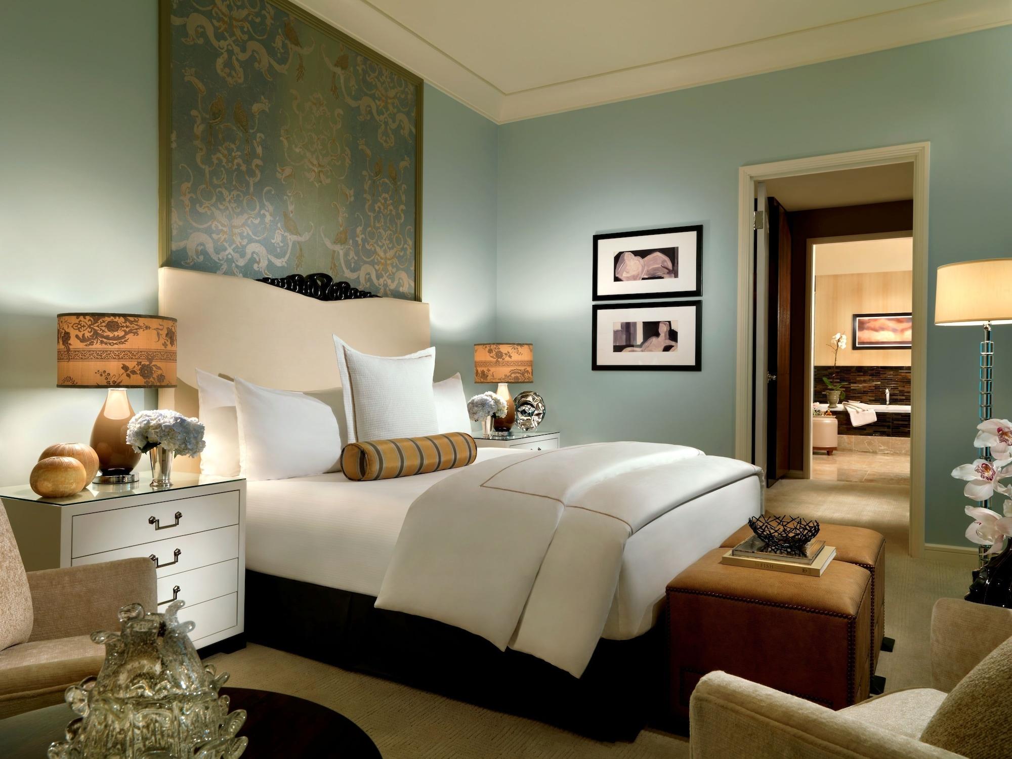 Trump International Hotel Лас Вегас Екстериор снимка The photo shows a well-decorated bedroom with a light blue color scheme. The bed is large with white linens and a decorative pillow. There are two stylish bedside lamps on either side of the bed, each with a patterned shade. On the wall above the bed
