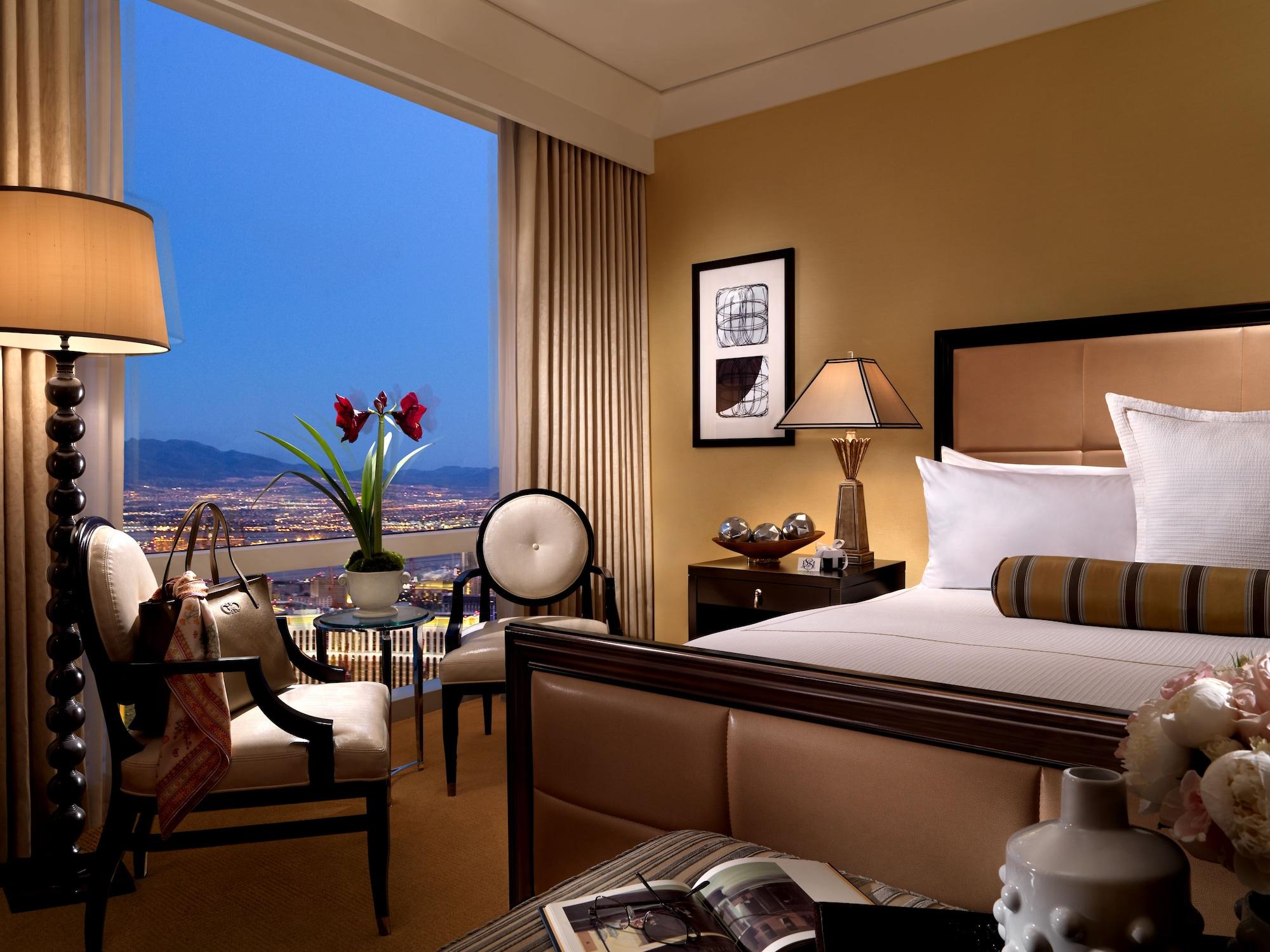 Trump International Hotel Лас Вегас Екстериор снимка The photo depicts a luxurious hotel room featuring an elegant design. There is a large bed with plush white bedding and decorative pillows. Next to the bed, there are bedside lamps providing soft lighting. A comfortable seating area includes a stylis