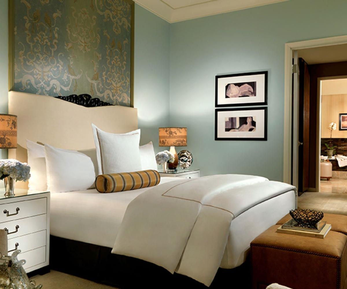 Trump International Hotel Лас Вегас Екстериор снимка The photo shows a stylish bedroom with a calm and elegant design. The walls are painted in a soft blue color, and there is a decorative panel above the bed, which features a floral or abstract pattern. The bed is dressed with white linens and decorat