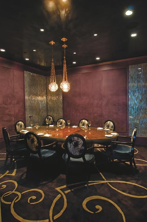 Trump International Hotel Лас Вегас Екстериор снимка The photo shows an elegant dining room featuring a large, round table with a polished wooden surface, surrounded by several chairs. The chairs have ornate designs, possibly with floral or bird motifs. Above the table, there are two decorative pendant