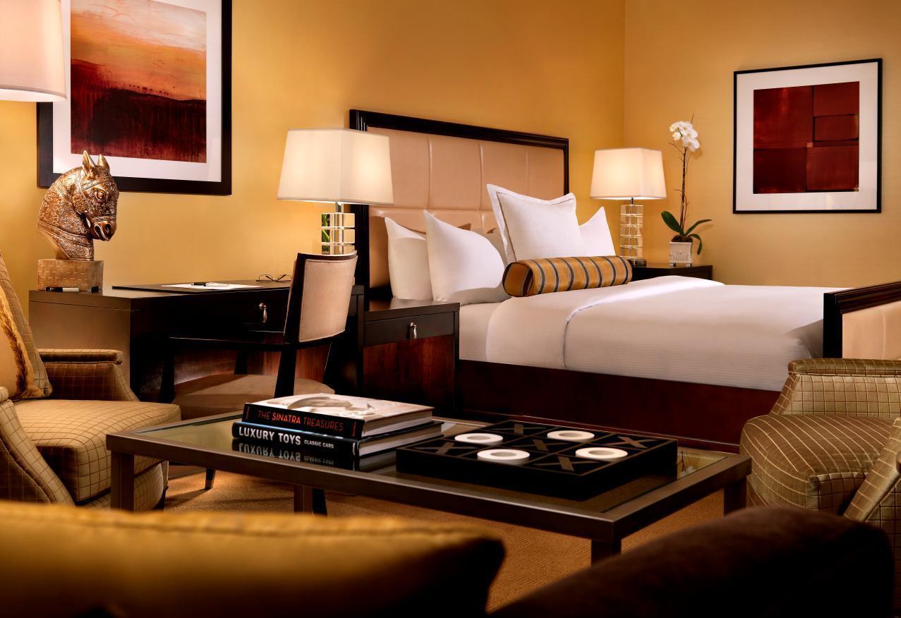 Trump International Hotel Лас Вегас Екстериор снимка The photo depicts a stylish hotel room or guest suite. The room features a large bed with white bedding and decorative pillows, framed by a softly colored wall. On either side of the bed, there are modern table lamps providing warm illumination. 

A 