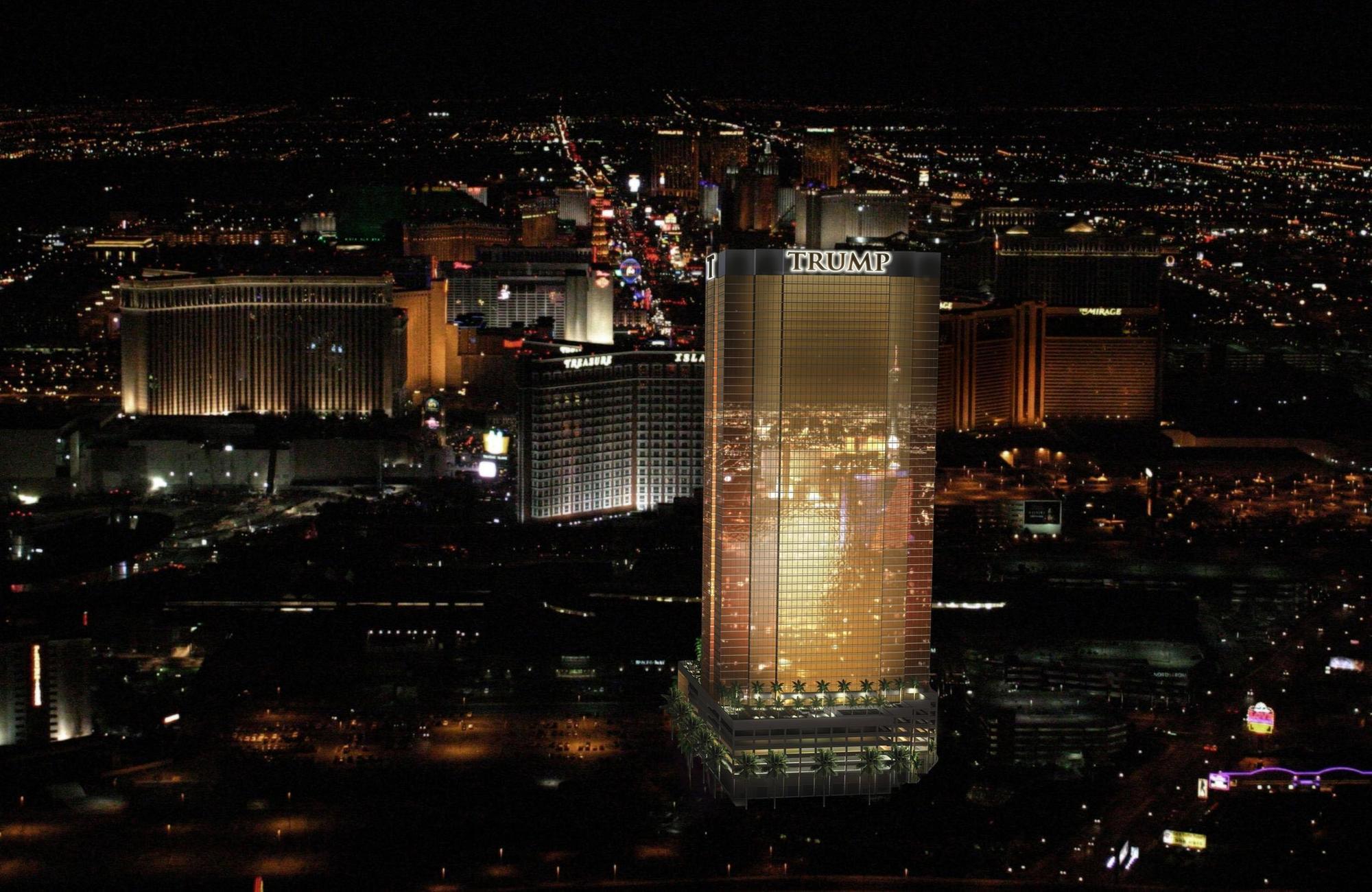 Trump International Hotel Лас Вегас Съоръжения снимка The photo shows a nighttime aerial view of a city, likely Las Vegas, featuring a brightly lit skyline. Prominent in the foreground is a tall building displaying the name "TRUMP." Surrounding buildings are also illuminated, showcasing a vibrant city s