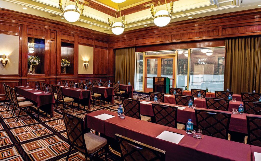 Trump International Hotel Лас Вегас Екстериор снимка The photo shows a well-appointed conference or meeting room. It features several rows of rectangular tables covered in maroon tablecloths, arranged to accommodate attendees. Each table has a notepad and a bottle of water. The room has a polished wood