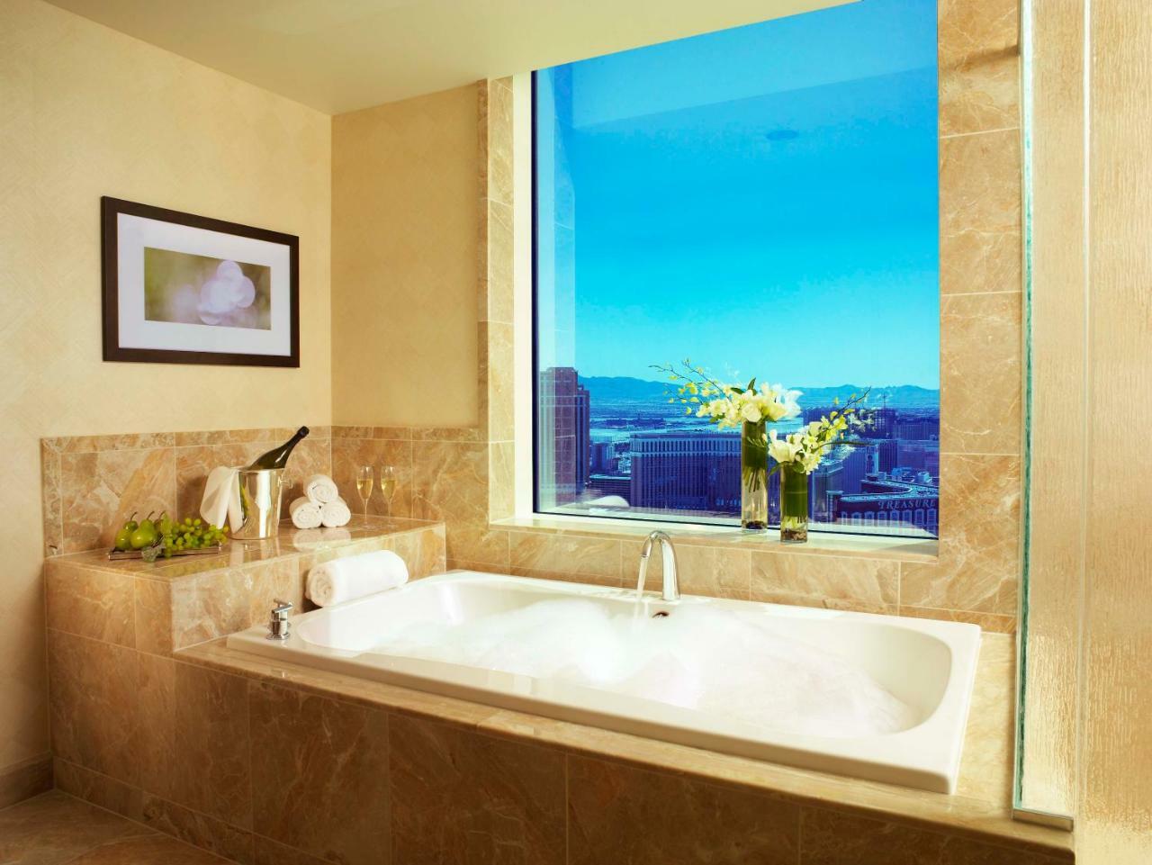 Trump International Hotel Лас Вегас Екстериор снимка The photo depicts a luxurious bathroom featuring a modern freestanding bathtub positioned near a large window that offers a panoramic view. The window allows natural light to flood the space, showcasing a beautiful outdoor vista. The bathroom has war